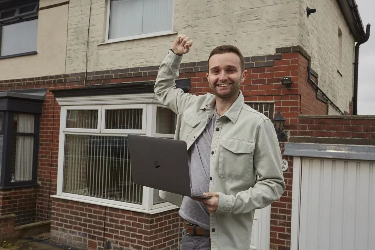 Adam Roebuck outside a home holding laptop